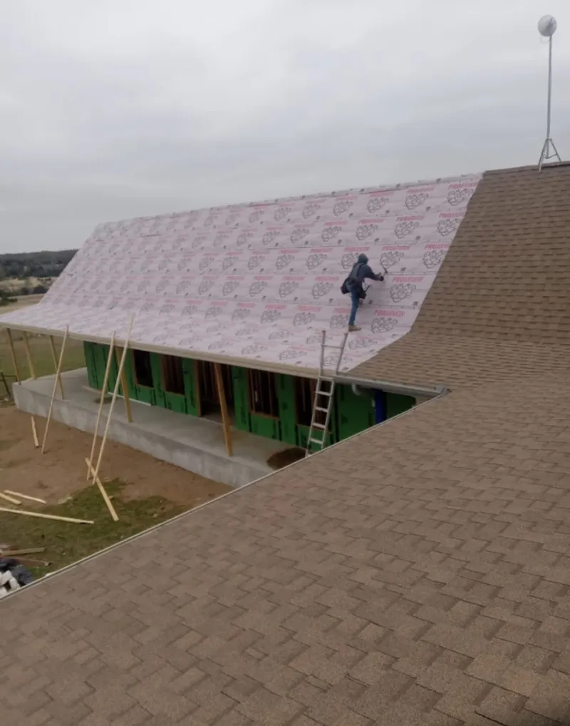 Worker preparing underlayment for a metal roof installation in Enoch